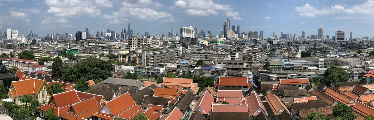 Bangkok from above — temple roofs in the foreground and the downtown towers behind.
