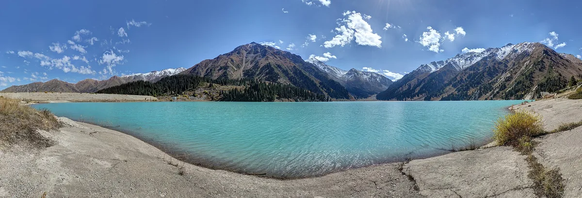 The turquoise water of Big Almaty Lake in a bowl of snow-topped peaks.