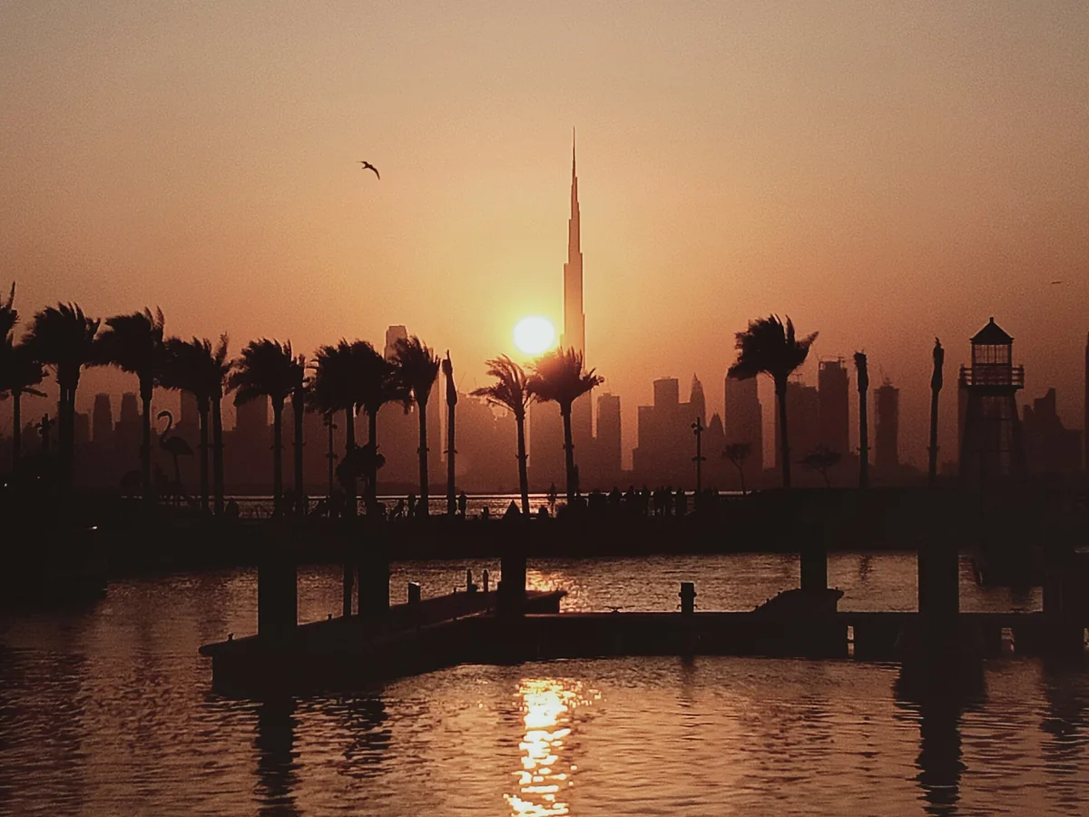 The Burj Khalifa in silhouette at sunset, the sun dropping behind the tower.