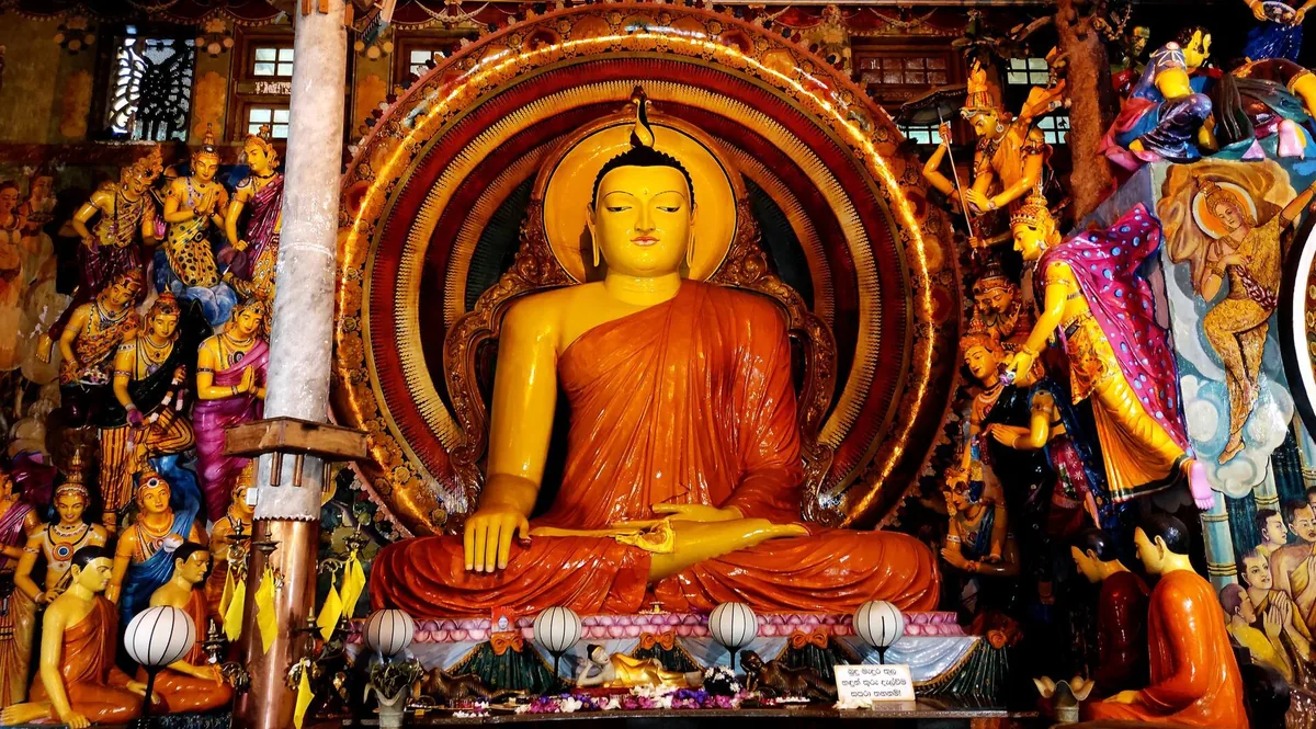 The seated Buddha inside Gangaramaya Temple, Colombo, ringed with painted figures.