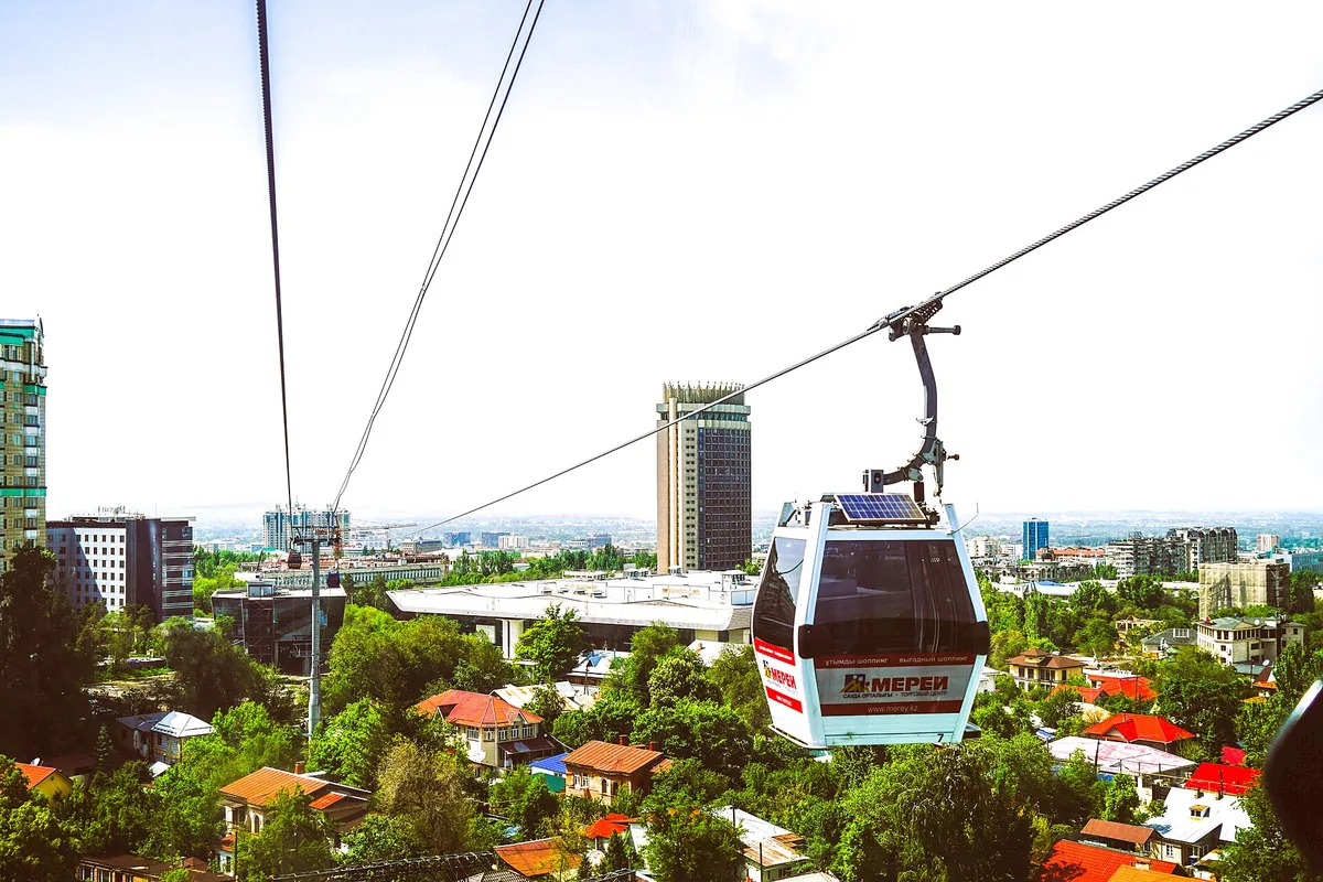 A cable car cabin climbing to Kok-Tobe hill above the rooftops of Almaty.