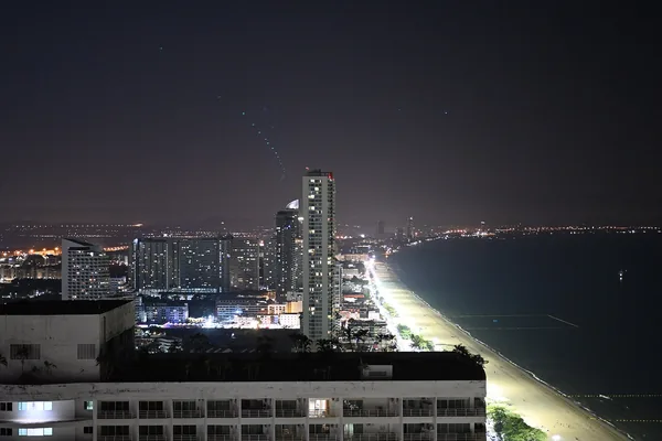 The curve of Pattaya bay at night, the beach road lit along the shoreline.