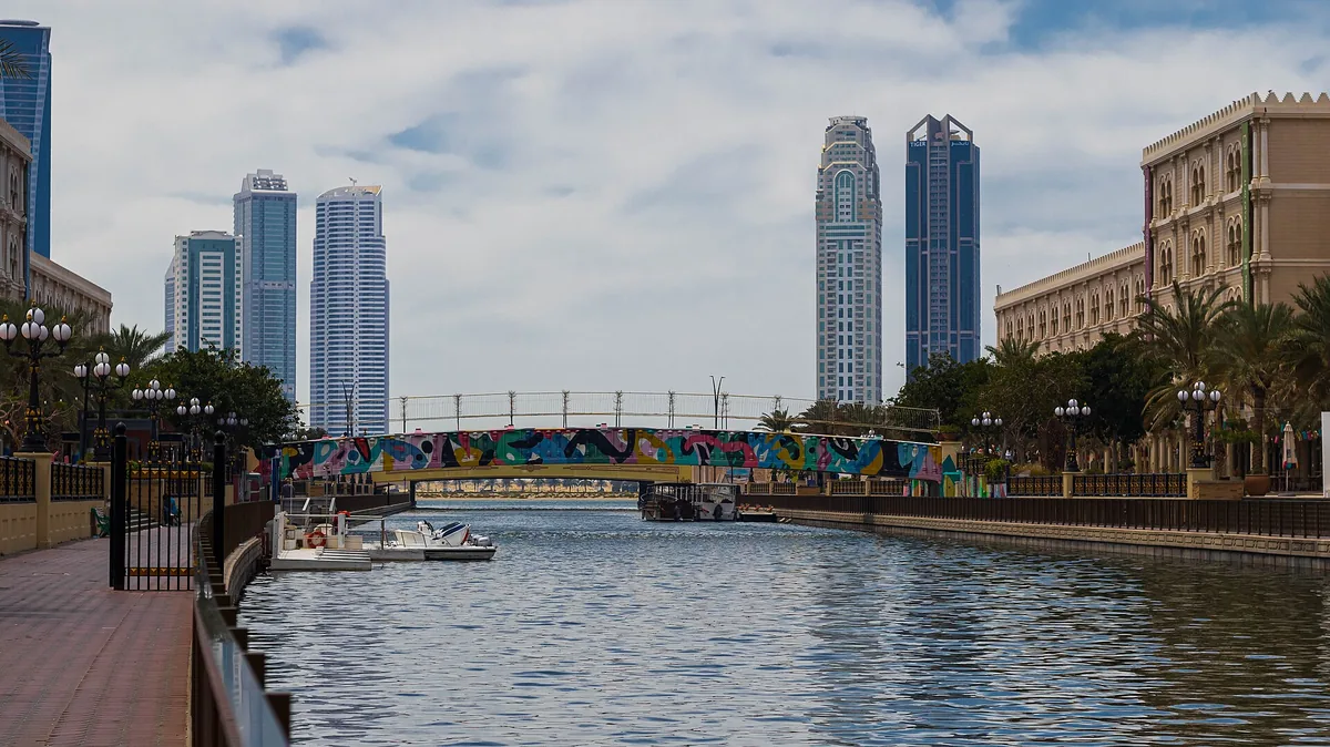 The canal at Al Qasba, Sharjah, with its painted footbridge and the towers behind.