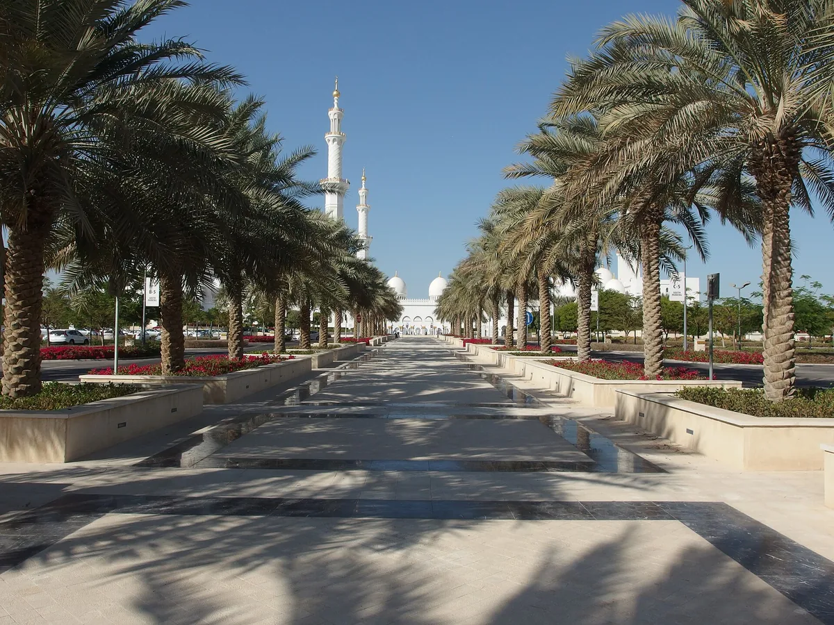 The palm avenue leading to the white domes and minarets of the Sheikh Zayed Grand Mosque, Abu Dhabi.