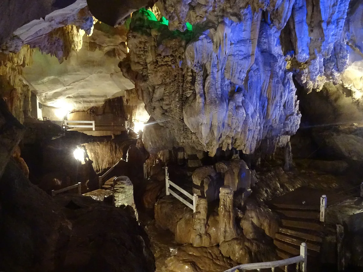 The lit interior of Tham Jang cave at Vang Vieng, stalactites picked out in blue and violet.