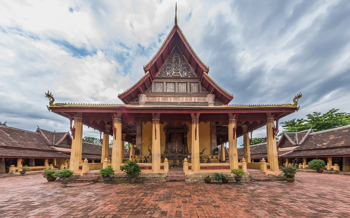 The tiered roof and columned frontage of Wat Sisaket in Vientiane, seen across the courtyard.