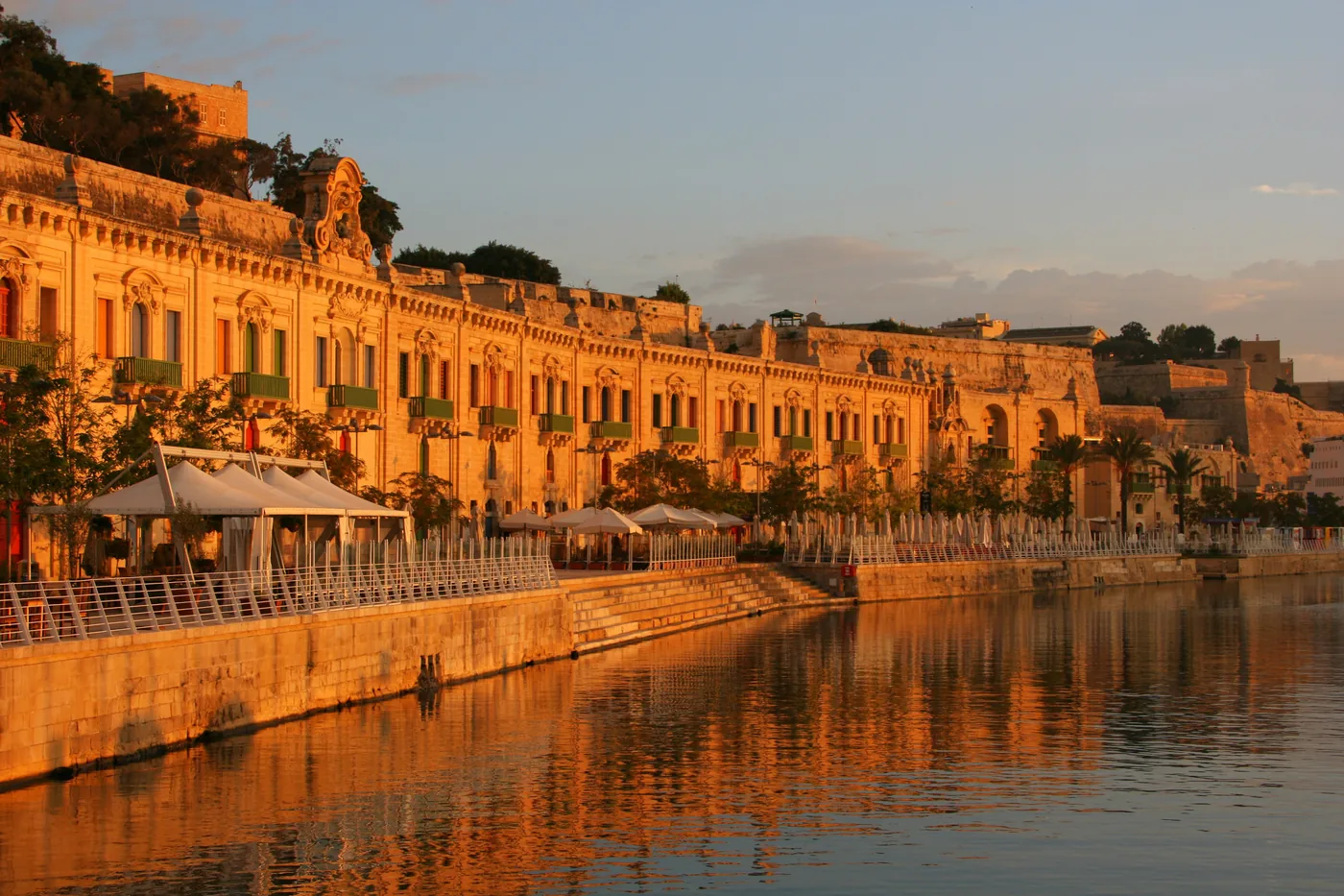The honey coloured waterfront of Valletta reflected in the harbour at sunset, Malta
