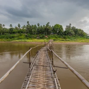 A bamboo footbridge across the Mekong to Luang Prabang, hills behind.